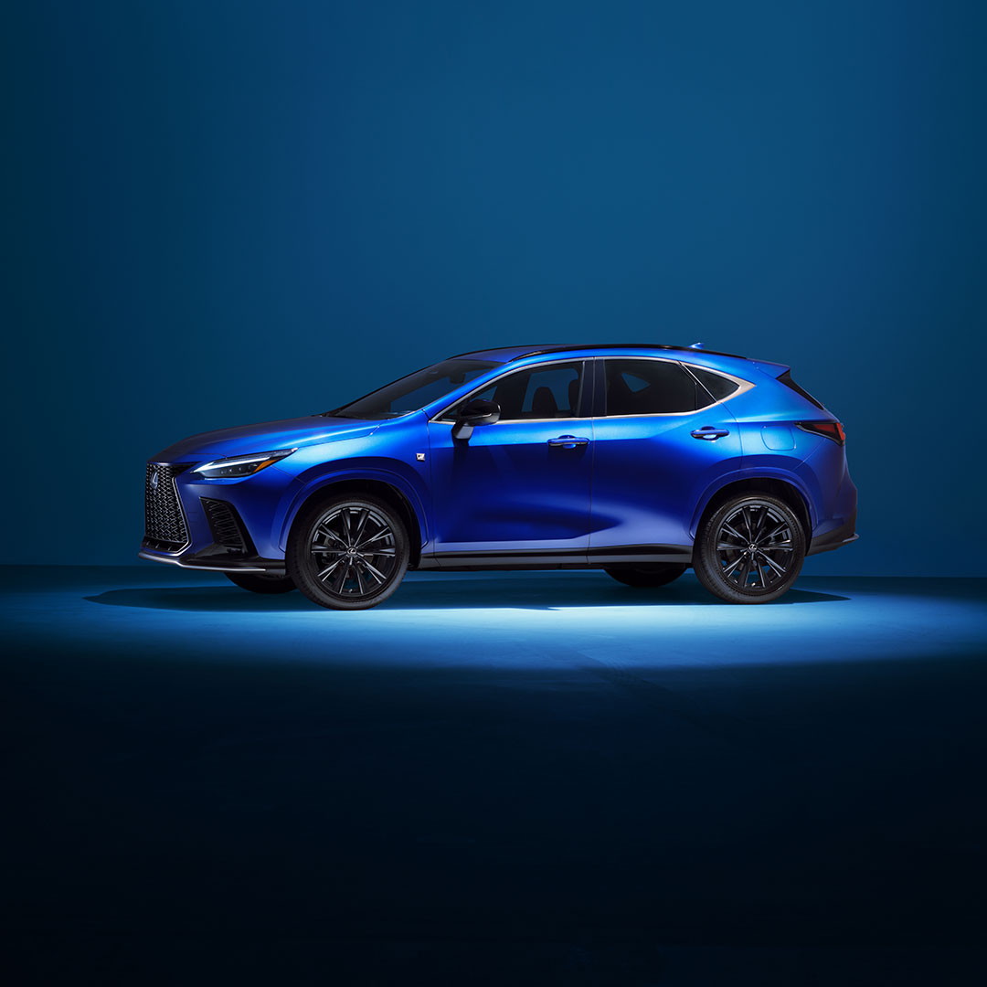 A bright blue 2021 NX F Sport sits illuminated in studio lights.