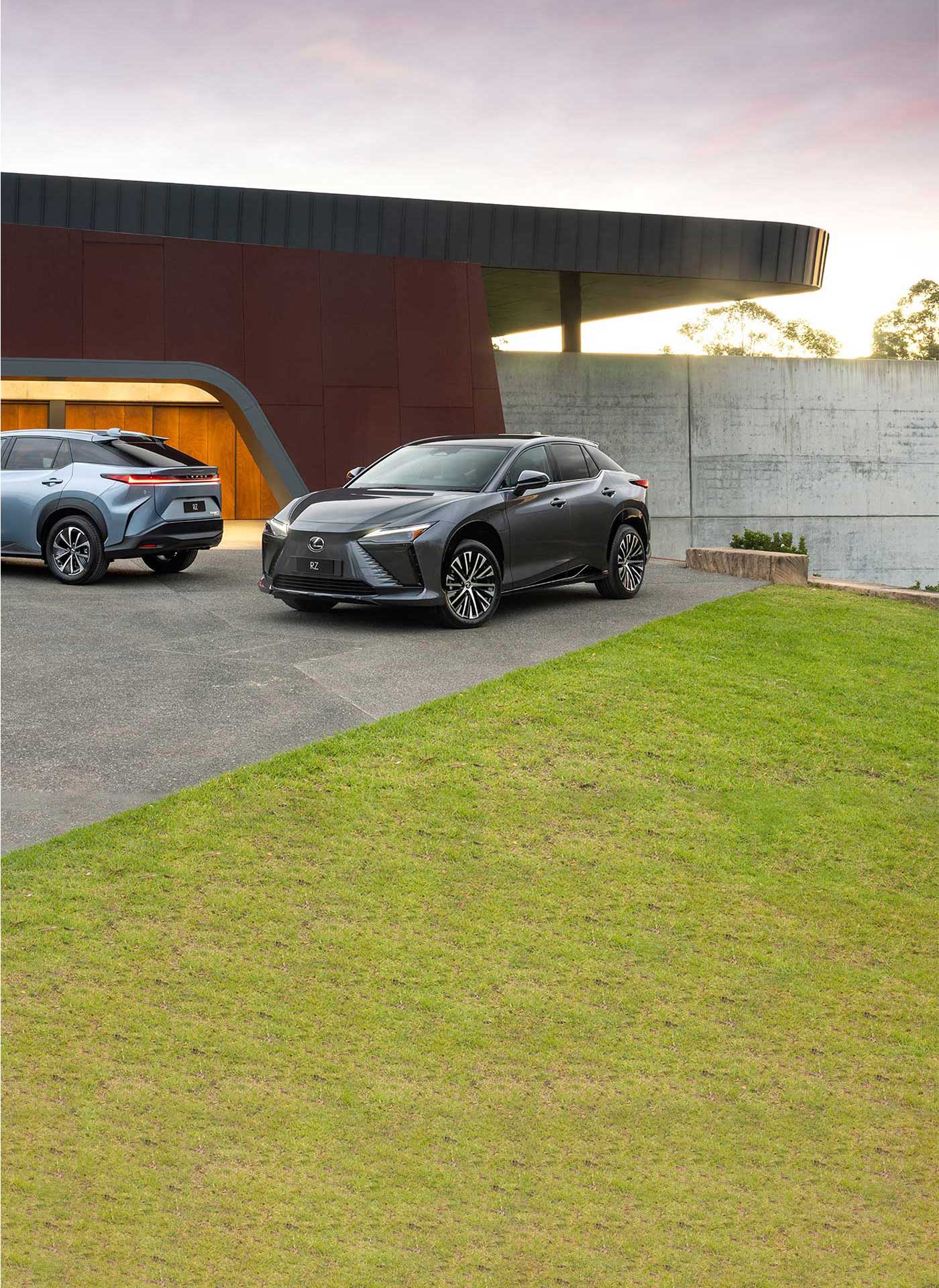 Two Lexus RZ All Electric vehicles are parked at the front of a luxury home